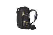 The Persist™ Women's 30L Endless Promise® All-Adventure Backpack by NEMO Equipment in black and gray with yellow zippers, crafted from sustainable materials, offers multiple compartments. Seen side view, it's perfect for mountain adventurers seeking durable and functional gear.
